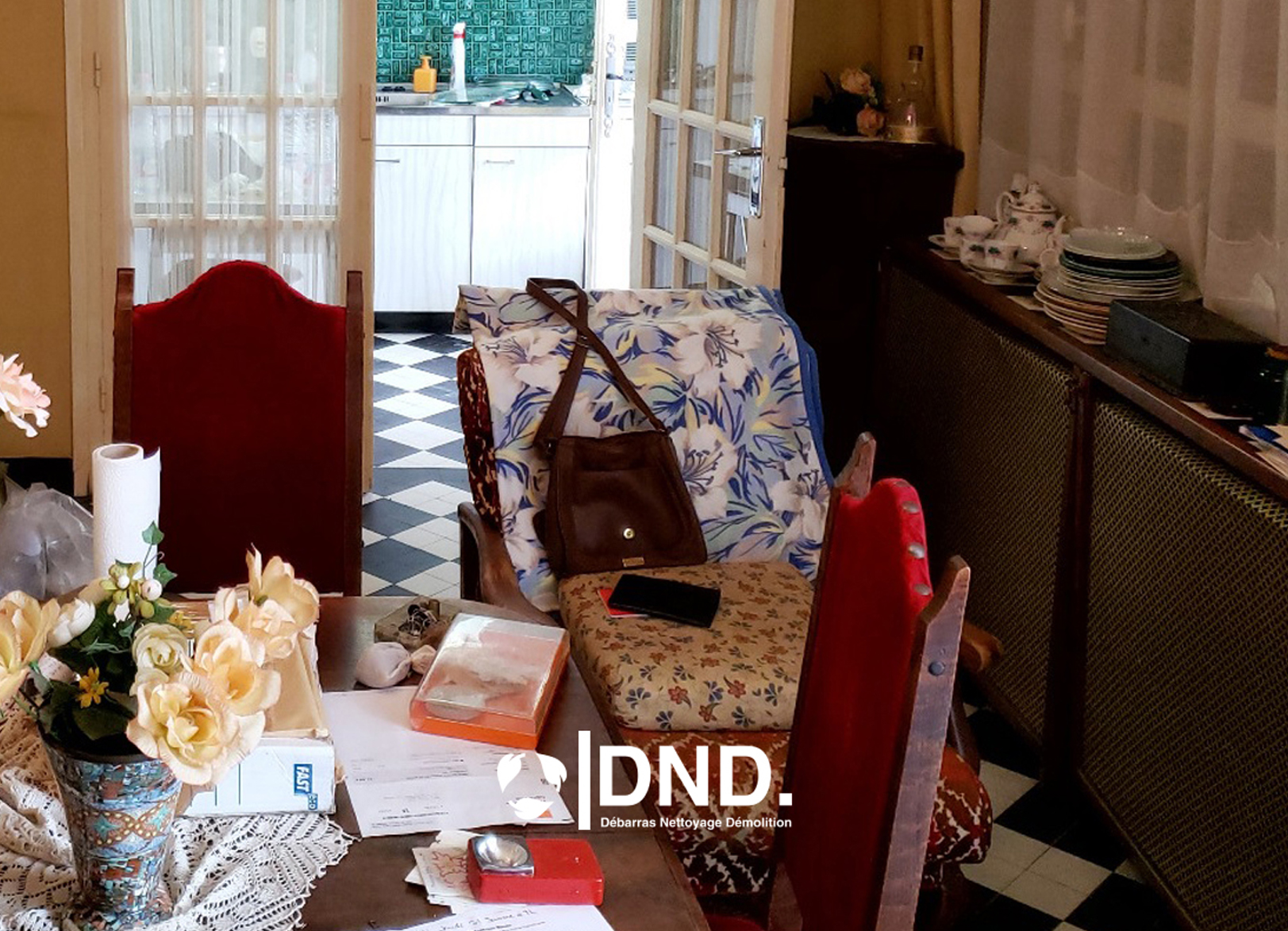 Salle à manger encombrée avec des objets divers sur la table et une cuisine en arrière-plan, nécessitant un service de débarras suite à un déménagement en Île-de-France